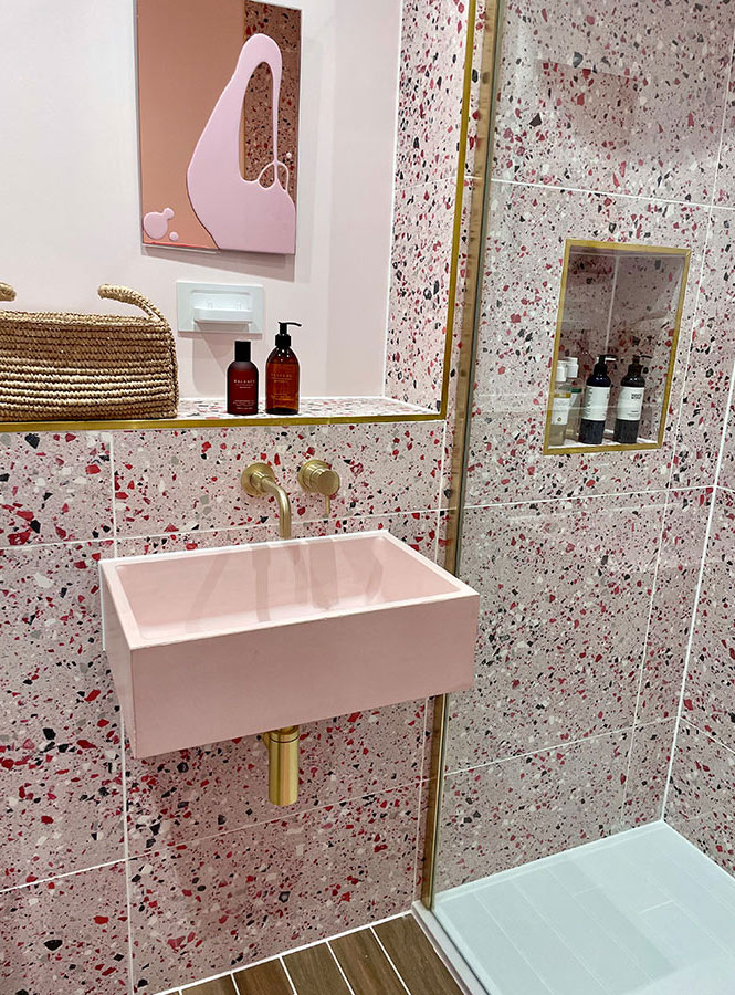 Pink concrete sink with gold tap in a pink terrazzo tiled bathroom