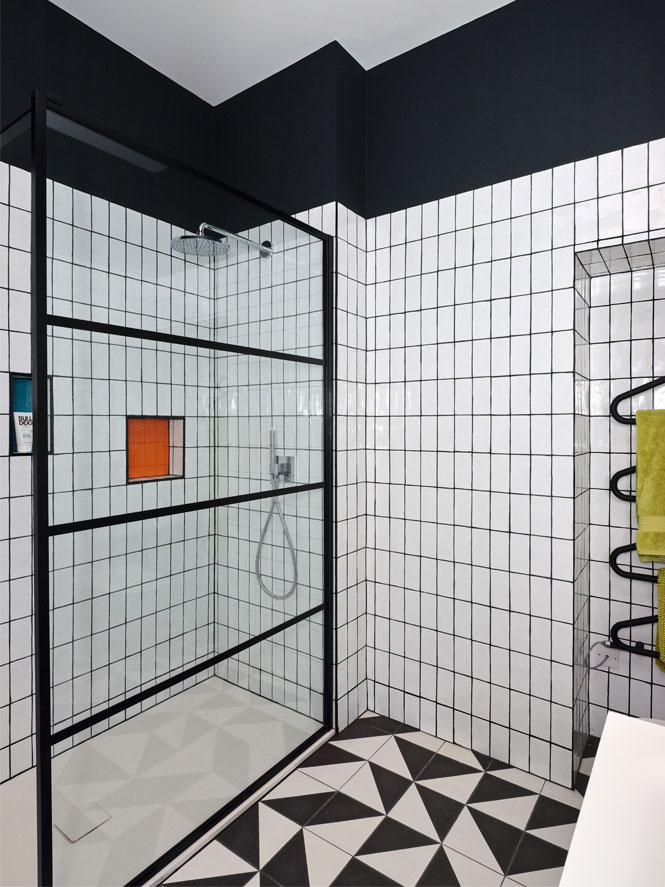 Monochrome bathroom with orange and blue niches to the shower and a lime green towel on the black radiator